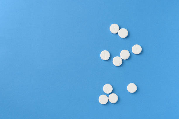 istock White round pills scattered on a blue background, top view. Medical pharmacy concept 1189683318