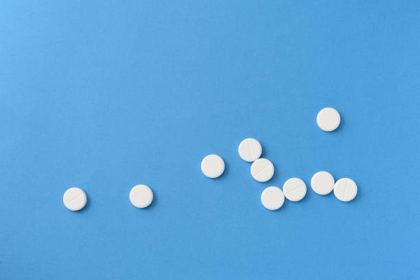 istock White round pills scattered on a blue background, top view. Medical pharmacy concept 1189683321