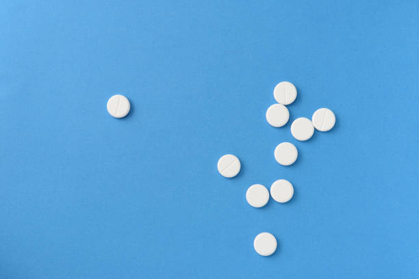istock White round pills scattered on a blue background, top view. Medical pharmacy concept 1189683323
