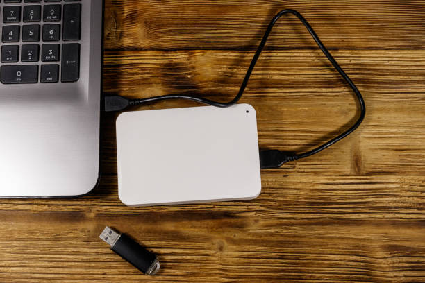 istock External HDD connected to laptop computer and USB flash drive on a wooden desk. Top view. Concept of data storage 1189688713