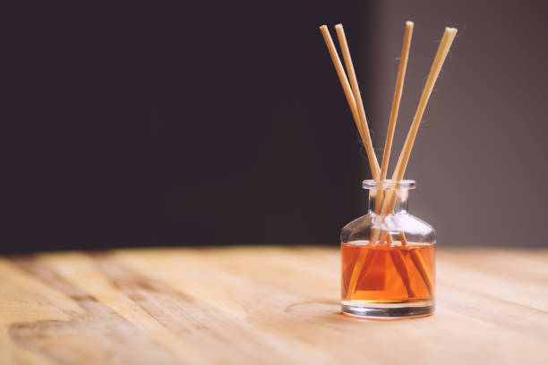 parfum d'air sous forme de bâtons liquides et en bois sur une table en bois - air freshener photos et images de collection