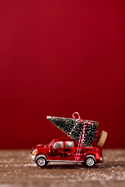 Christmas tree ties on top of a red mini car. Suitable for Christmas card.
