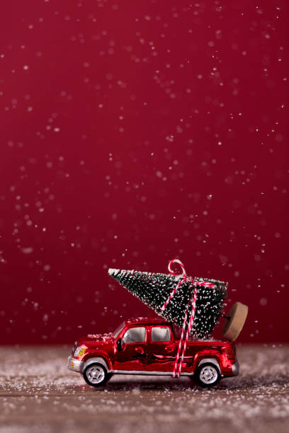 Christmas tree ties on top of a red mini car. Suitable for Christmas card.