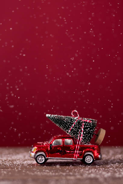 Christmas tree ties on top of a red mini car. stock photo