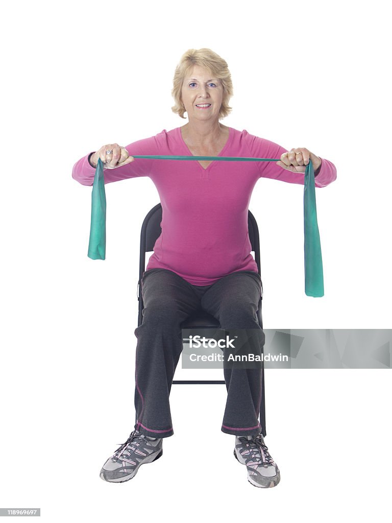Senior mujer haciendo ejercicios de resistencia con banda elástica de resistencia en silla - Foto de stock de Ejercicio físico libre de derechos