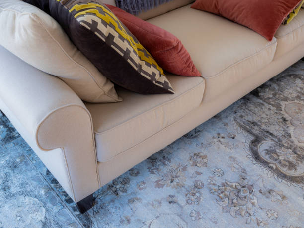 istock Partial view of cream sofa, colorful throw pillows and grey oriental rug 1189697252