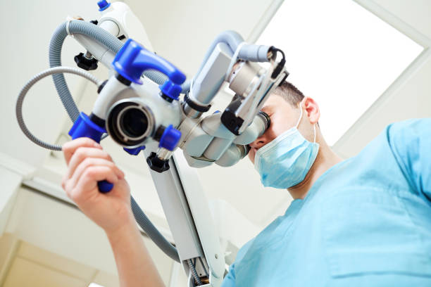istock Male dentist looking through a microscope in a dental office 1189703821