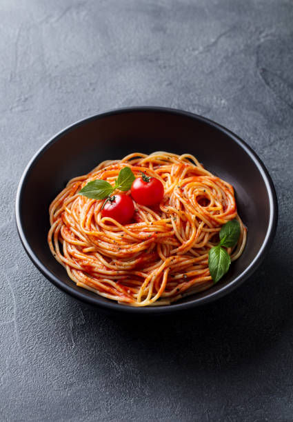 istock Pasta, spaghetti with tomato sauce in black bowl. Grey stone background. 1189706581