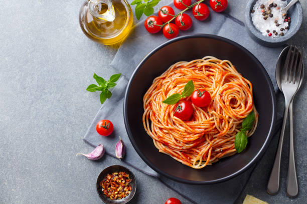pasta, espaguetis con salsa de tomate en tazón negro sobre fondo gris. copiar espacio. vista superior. - salsa de tomate fotografías e imágenes de stock