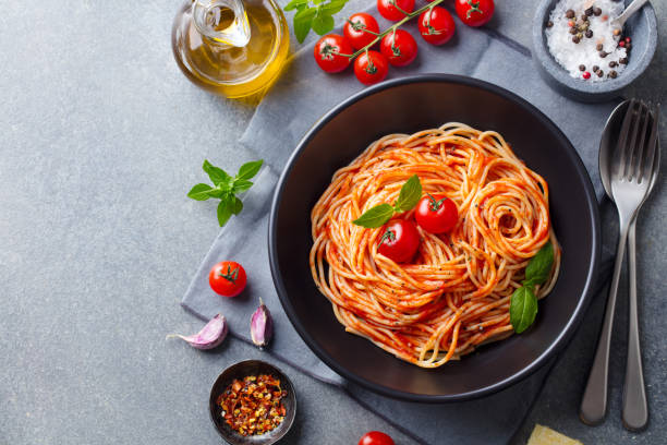 Pasta, spaghetti with tomato sauce in black bowl on grey background. Copy space. Top view. Pasta, spaghetti with tomato sauce in black bowl on grey background. Copy space. Top view. tomato sauce stock pictures, royalty-free photos & images