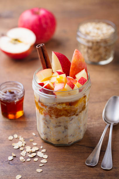 Overnight oats, bircher muesli with apple in glass jars on wooden background. stock photo