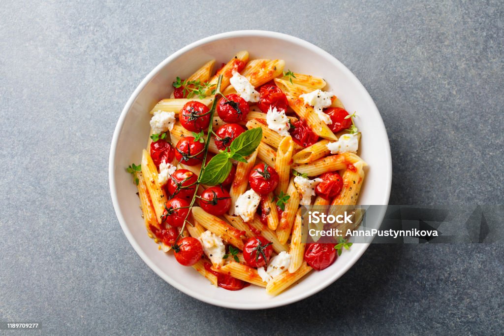 Pasta penne dengan tomat panggang, saus, keju mozzarella. Latar belakang batu abu-abu. Tampilan atas. - Bebas Royalti Pasta Foto Stok Pasta penne dengan tomat panggang, saus, keju mozzarella. Latar belakang batu abu-abu. Tampilan atas. - Bebas Royalti Pasta Foto Stok