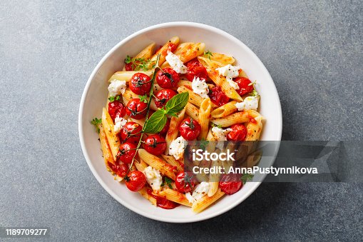 istock Pasta penne with roasted tomato, sauce, mozzarella cheese. Grey stone background. Top view. 1189709277