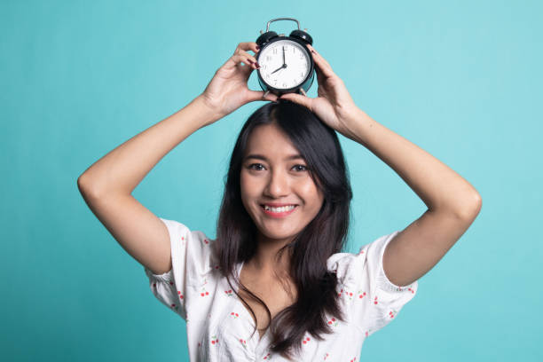 istock Young Asian woman smile with a clock. 1189713665