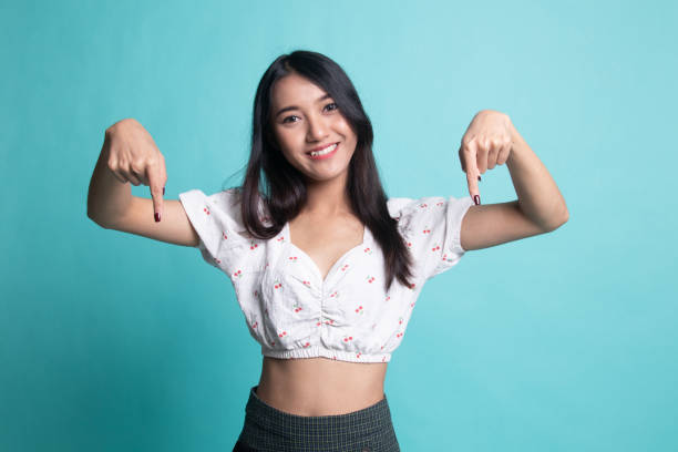 istock Beautiful young Asian woman point down to blank space. 1189715070