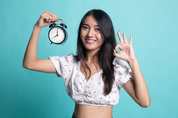 istock Young Asian woman show OK with a clock. 1189717565