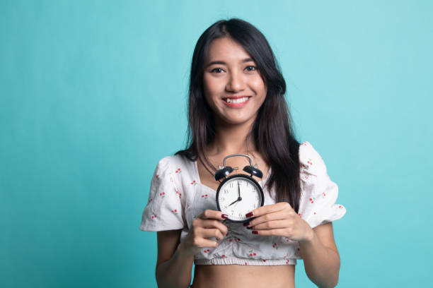 istock Young Asian woman smile with a clock. 1189717660