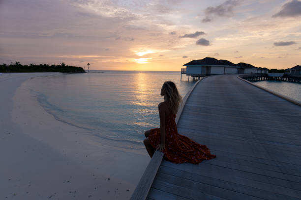 istock Elegant woman relaxing on a pier at sunset. 1189718151