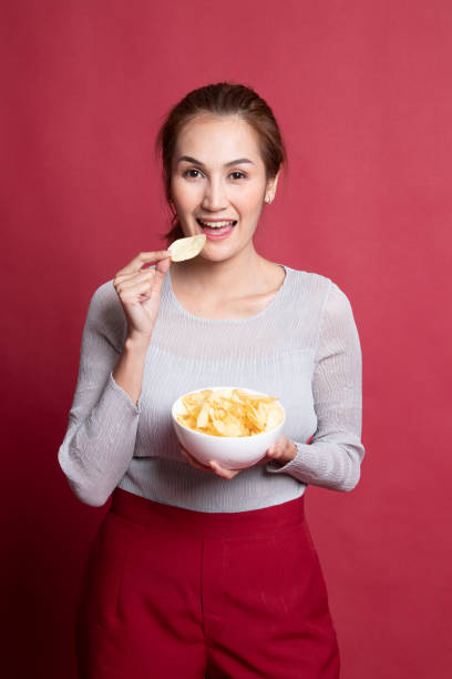 istock Young Asian woman eat potato chips. 1189719605