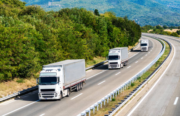 istock Three white Lorry trucks in line on a country highway 1189720809