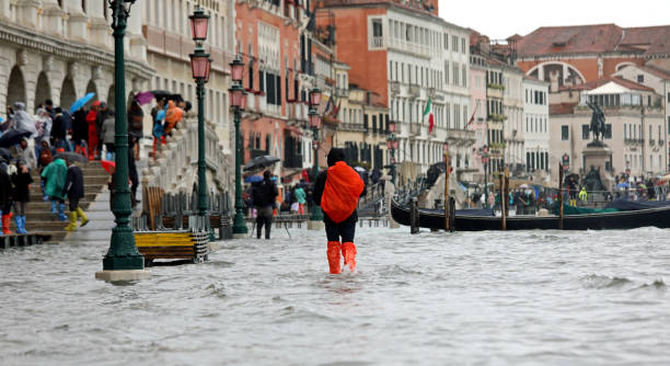 люди с зонтиками и плащом в дождливый день в венеции в - riva degli schiavoni стоковые фото и изображения