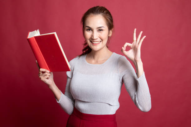 istock Young Asian woman show OK with a book. 1189721000