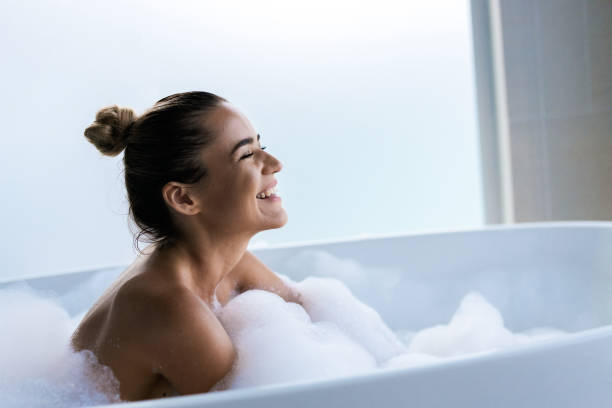 joven mujer feliz disfrutando en el baño de burbujas con los ojos cerrados. - bañera fotografías e imágenes de stock