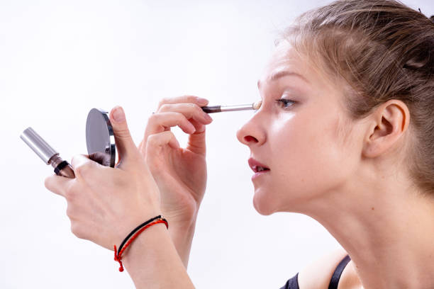 istock beautiful young cute girl puts eye shadow on a white background 1189722108