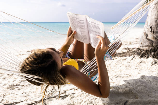 istock Relaxed woman reading a book in hammock on the beach. 1189724590