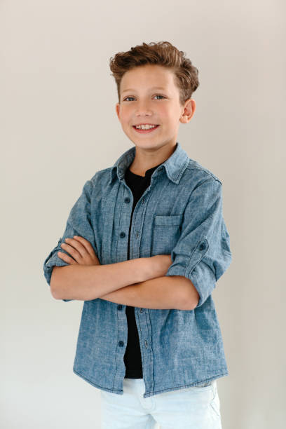 istock Smiling boy standing with arms crossed against a gray background 1189728198