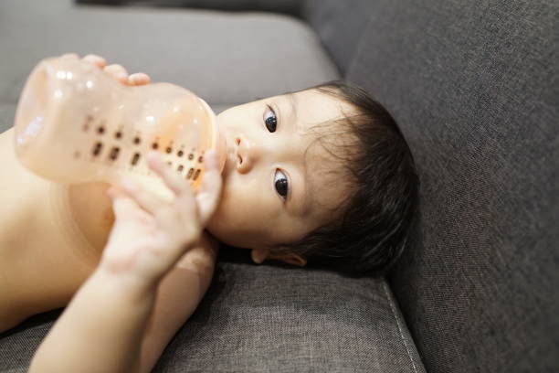 Asian baby boy toddler drinking milk from a milk bottle stock photo