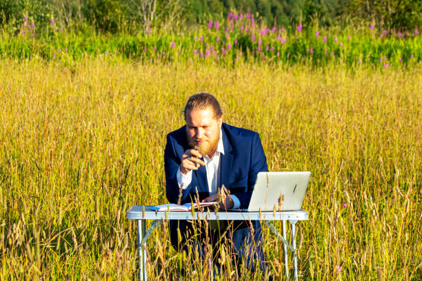 istock White caucasian man with a beard works at table on a laptop outdoors. Concept businessman outdoors. 1189732947