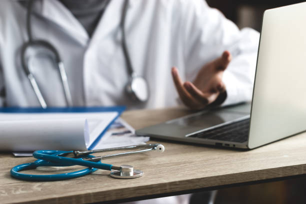 istock Medicine doctor hand explaining for patient at consulting room, working on laptop computer on desk in clinic, Focus stethoscope on foreground table in hostpital. Healthcare and medical concept. 1189736624