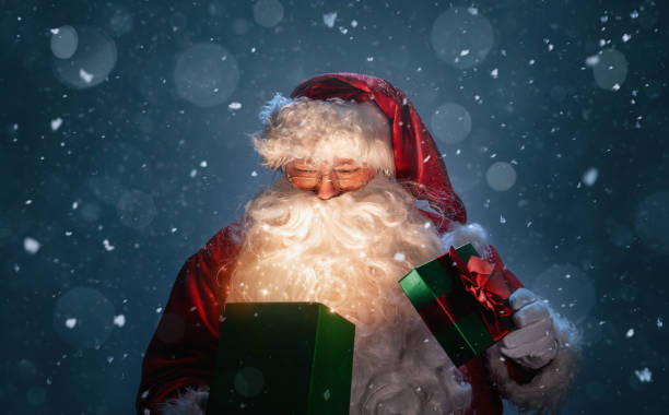 Happy Santa Claus opening magic christmas gift box Happy Santa Claus opening christmas gift box over snowy blue background with copy space north pole photos stock pictures, royalty-free photos & images
