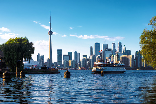 Toronto, Ontario, Canada, view of iconic Toronto skyline showing ferry boat arriving at Centre Island on a sunny day during fall season.