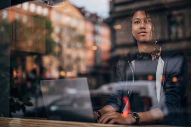 Hipster man sitting in the coffee shop and working on laptop