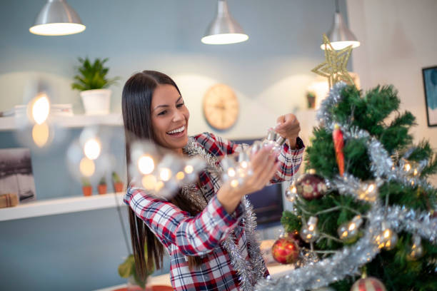 istock Beautiful woman decorating Christmas tree at home. 1189744247