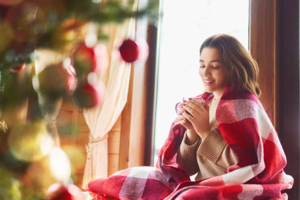 woman sitting by the window - sensuality lifestyles cheerful comfortable imagens e fotografias de stock