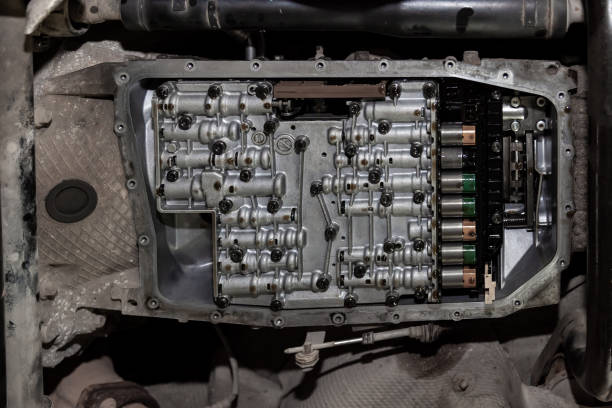 vista inferiore del fondo dell'auto con la padella di trasmissione rimossa e una vista dei solenoidi lubrificati con olio durante la riparazione e la manutenzione in officina per i veicoli. - putting together foto e immagini stock