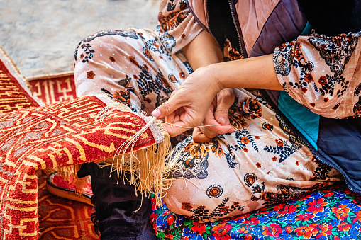 Detail of a female uzbek carpet weaver weaving a typical oriental uzbek silk carpet in Itchan Kala Old Town, Xiva - Khiva - Chiva, Xorazm Region, Uzbekistan, Central Asia