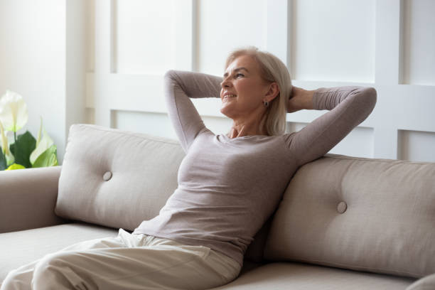 istock Happy middle aged retired woman relaxing on comfortable sofa. 1189748792