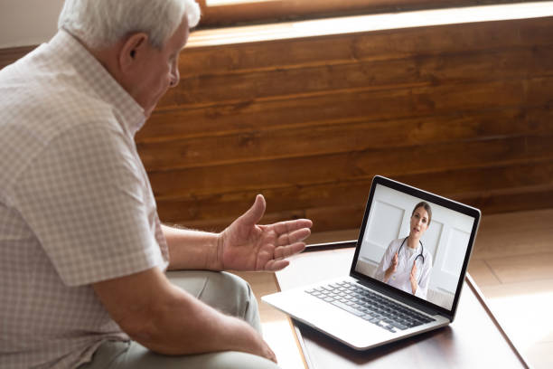 concentrándose en la consulta de pacientes de los años 80 con el médico a través de videollamada. - men middle senior adult human age fotografías e imágenes de stock