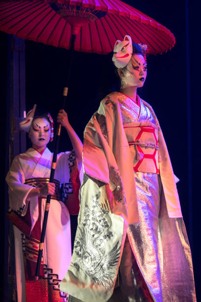 istock Traditional Japanese performance. Actress in traditional kimono and fox mark gradually goes and her assistant holds umbrella above her. 1189748863