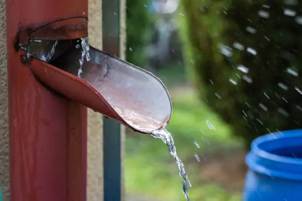 Raindrops in motion blur. Aluminum eaves in rain. Sustainable lifestyle in garden