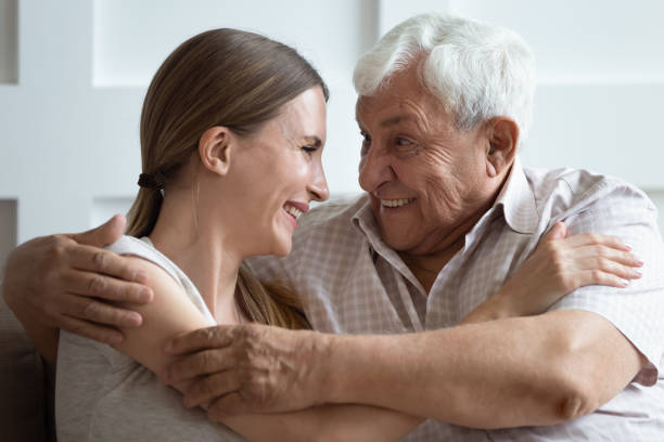 Close up head shot bonding two generations family embracing. Close up head shot bonding two generations family embracing, enjoying sweet tender moment at home. Happy young woman communicating, chatting with pleasant smiling 70s father, sitting on couch. father daughter 80s stock pictures, royalty-free photos & images