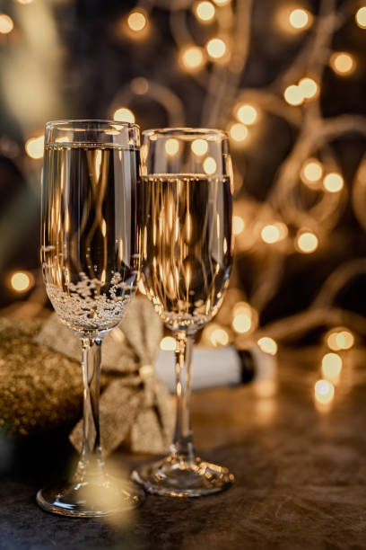 istock two champagne flute with shiny bottle on dark background with lights 1189755130