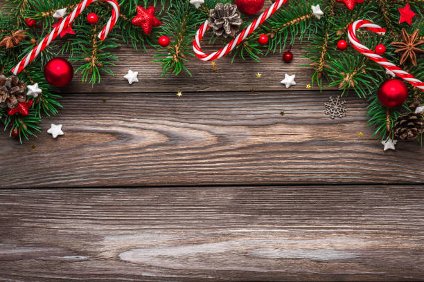 istock Christmas and Happy New Year composition. Fir tree branches, red holiday decorations and candy on rustic wooden table 1189756890
