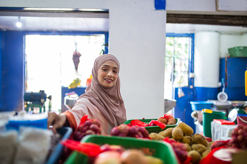 A Muslim female is choosing groceries in the market