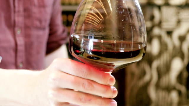 Barman at work. Male hand stirring a wine glass with red wine in it. 4K