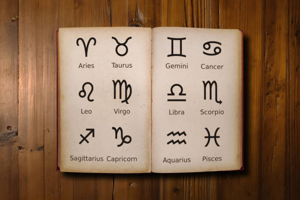 Opened astrology book filled with zodiac signs Close-up on an open Astrology book filled with zodiac signs in its middle. cancer astrology sign photos stock pictures, royalty-free photos & images
